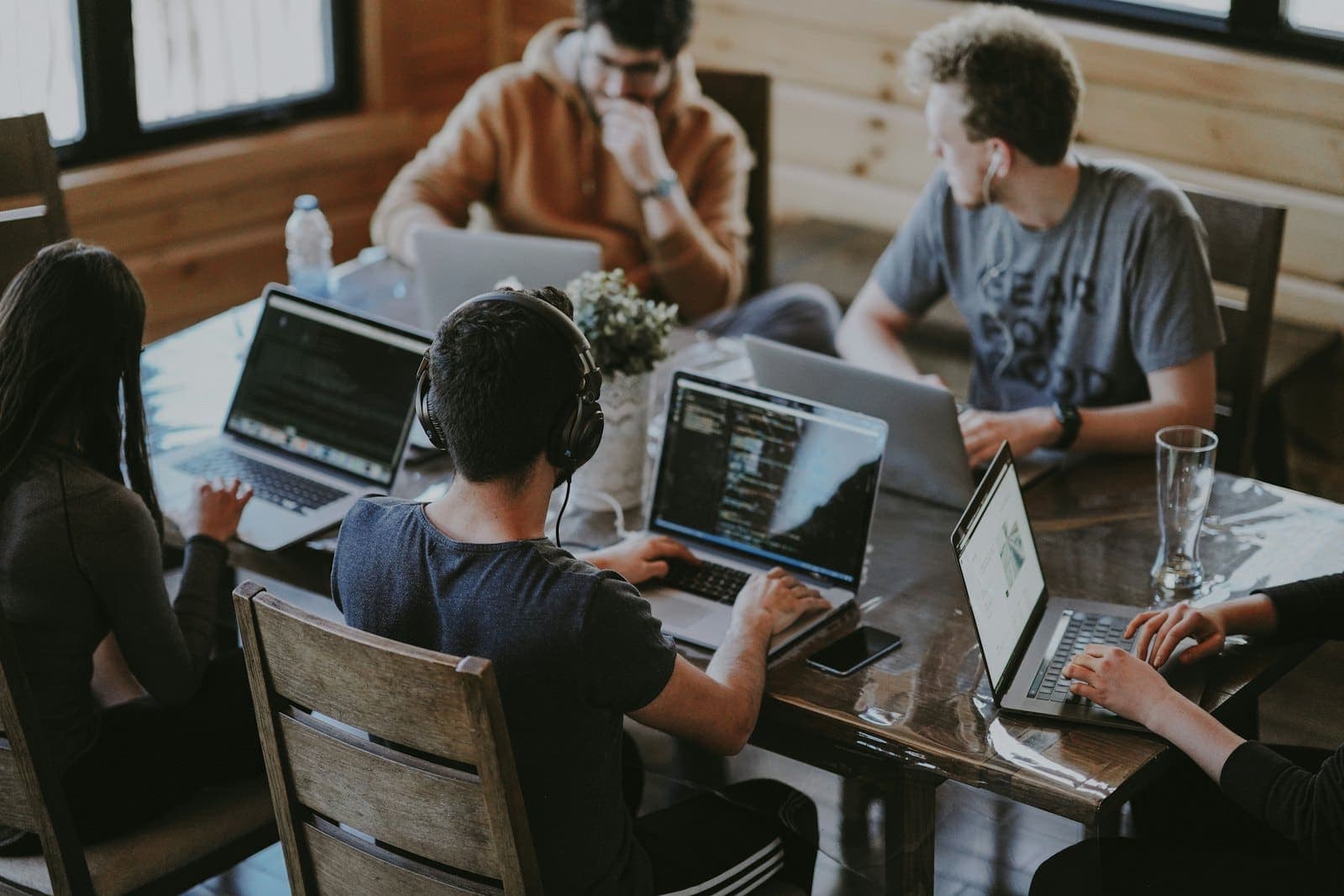 Team working together on laptops around a wooden table